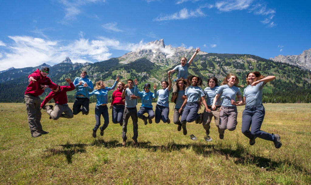 The 2023 YCP participants jump with the Teton mountain range as their backdrop.