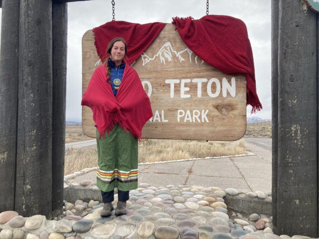 Cameran stands with Grand Teton National Park wearing red shawls to bring awareness for missing and murdered Indigenous Peoples.